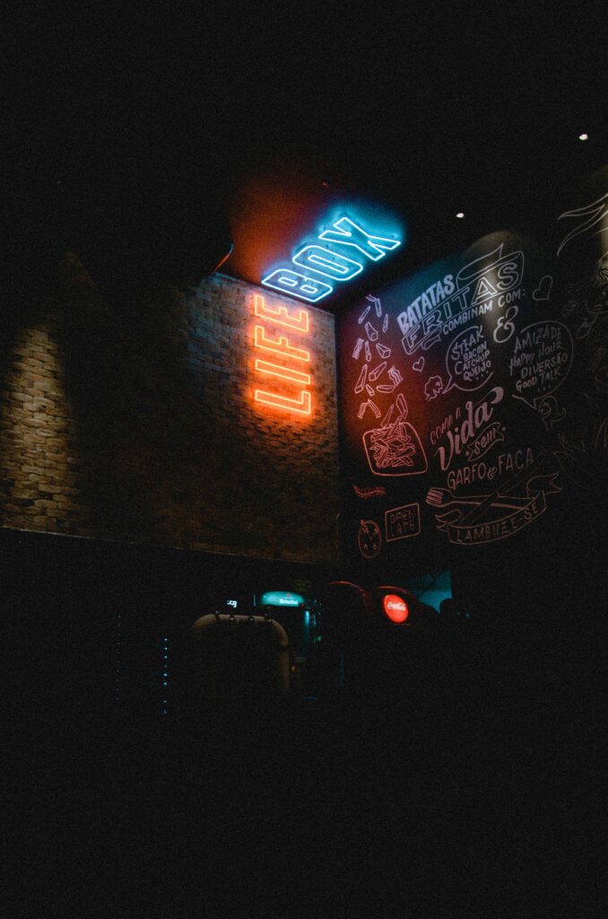 Neon 'LIFE BOX' sign glowing in a dimly lit urban environment with graffiti art.